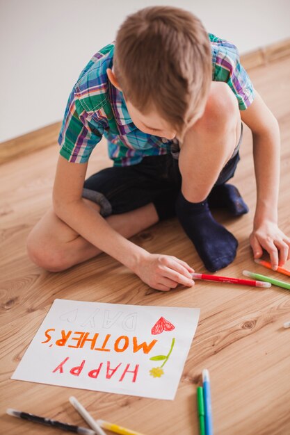 Niño concentrado usando lápices de colores para su cartel