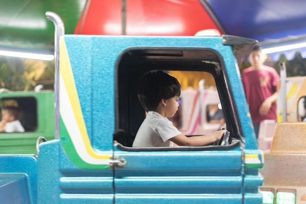 Niño conduciendo camión de juguete en el parque de atracciones