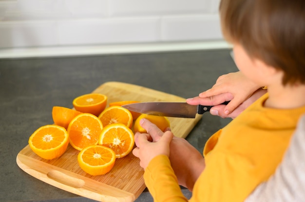 Niño cortando naranjas en mitades