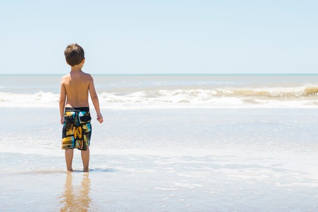 Niño en la costa en el agua