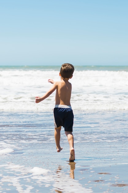Niño en la costa corriendo en el agua