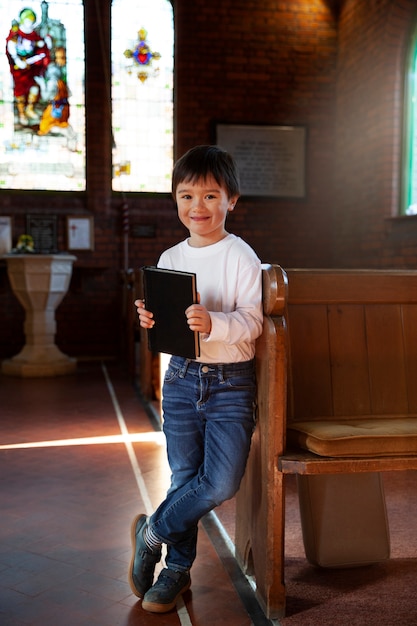 Niño cristiano feliz de tiro completo en la iglesia