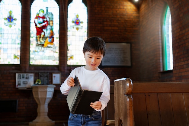 Foto gratuita niño cristiano feliz de tiro medio en la iglesia