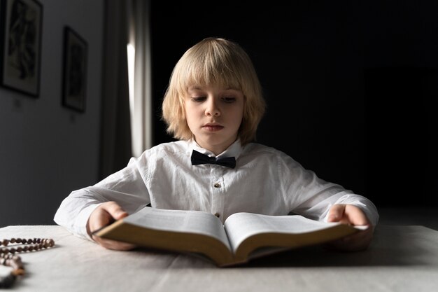 Niño cristiano de tiro medio leyendo la biblia