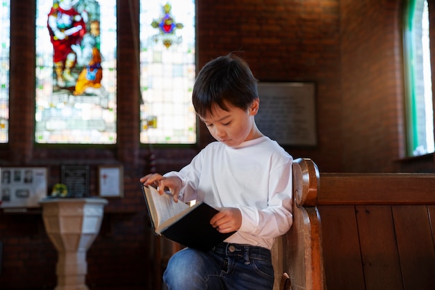 Niño cristiano de tiro medio leyendo la biblia