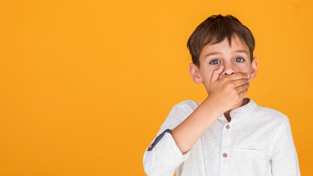 Niño cubriendo su boca con espacio de copia