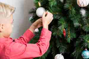 Foto gratuita niño decorando árbol de navidad