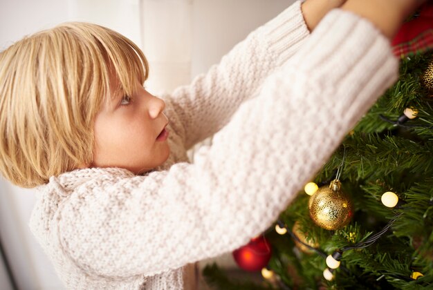 Niño decorar el árbol de Navidad en casa