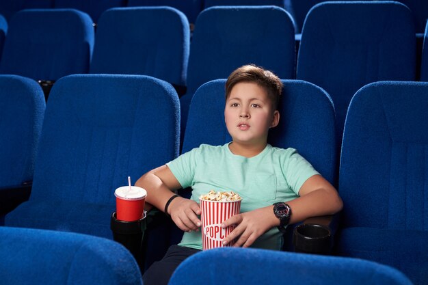 Niño descansando y disfrutando de la película de acción en el cine