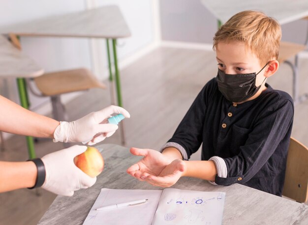 Niño desinfectando sus manos antes de comer una manzana