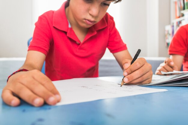 Niño dibujando con pluma en la mesa