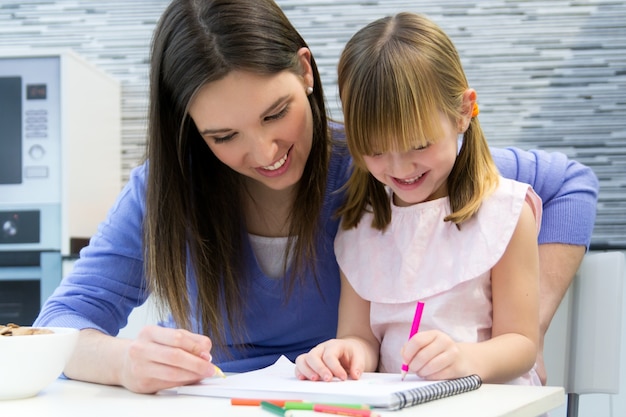 Niño dibujo con lápices de colores con su mamá en casa