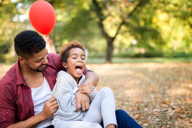 El niño disfruta y se ríe mientras el padre le hace cosquillas