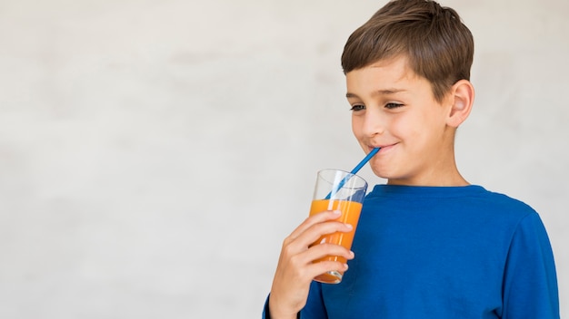 Niño disfrutando de su jugo de naranja con espacio de copia