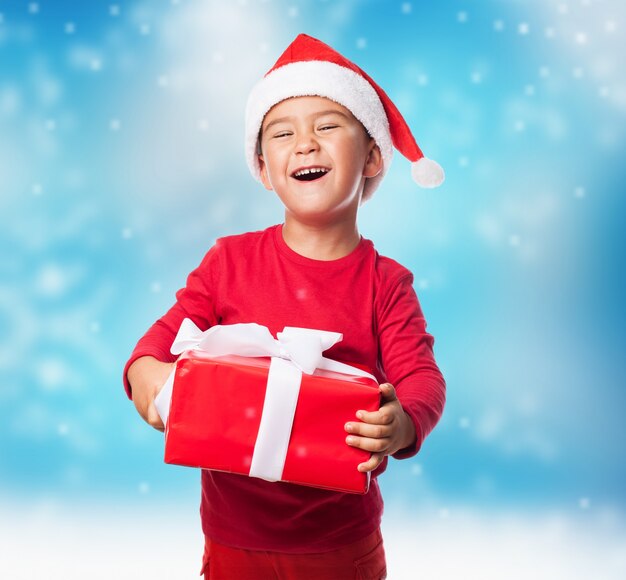 Niño divertido agarrando su regalo de navidad con las dos manos