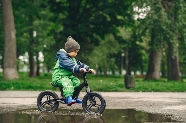 Foto gratuita niño divertido en botas de lluvia jugando en un parque de lluvia