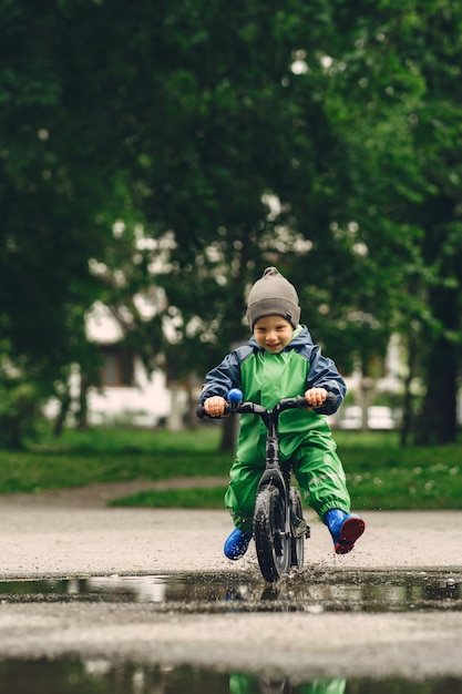 Niño divertido en botas de lluvia jugando en un parque de lluvia