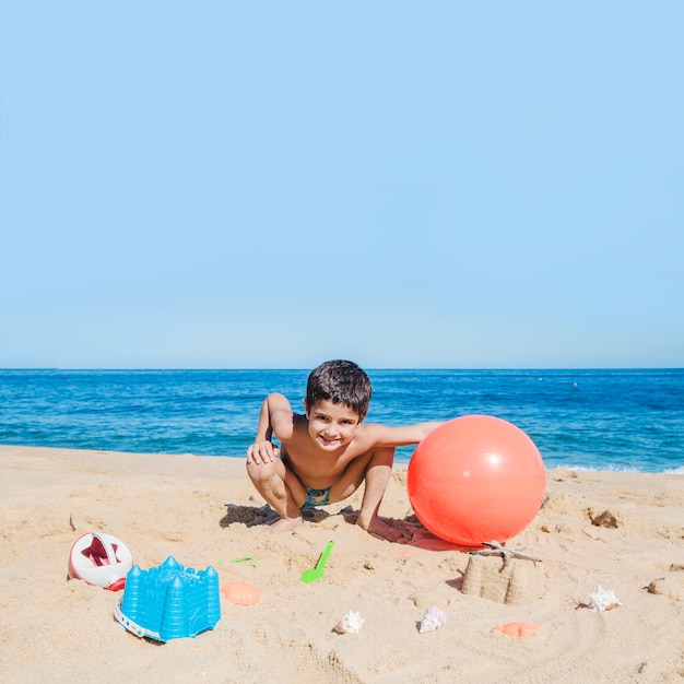 Niño divertido con pelota en la playa