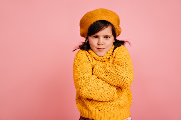 Niño divertido posando con los brazos cruzados. niña preadolescente viste ropa amarilla.