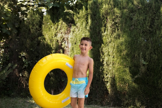 Foto gratuita niño divirtiéndose con flotador junto a la piscina