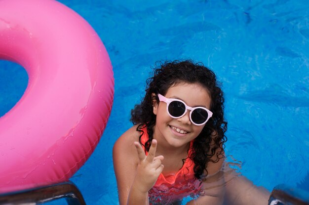 Foto gratuita niño divirtiéndose con flotador en la piscina