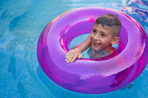 Niño divirtiéndose con flotador en la piscina