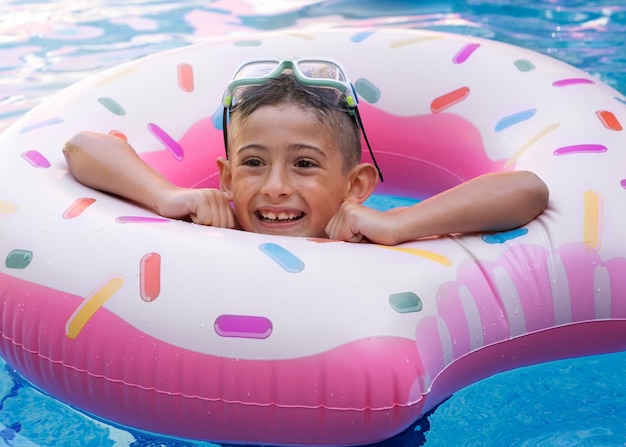 Niño divirtiéndose con flotador en la piscina