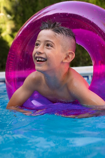 Niño divirtiéndose con flotador en la piscina