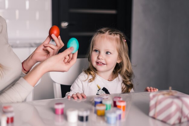 Niño divirtiéndose mientras pinta huevos de Pascua en la cocina