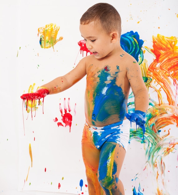 Niño divirtiéndose con pintura de diferentes colores