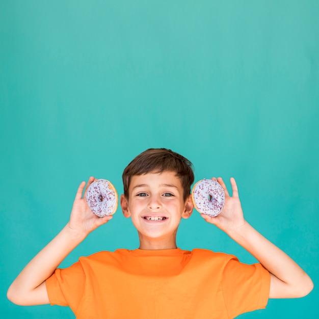 Foto gratuita niño con dos donas con espacio de copia