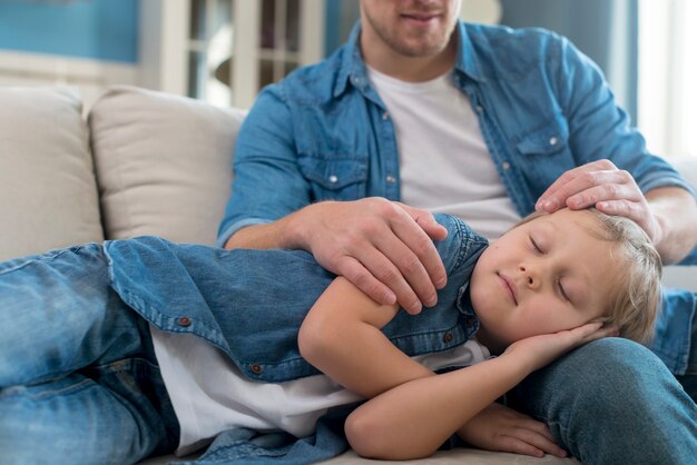 Niño durmiendo en las piernas del padre