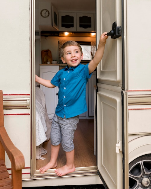 Foto gratuita niño echando un vistazo detrás de la puerta de su caravana