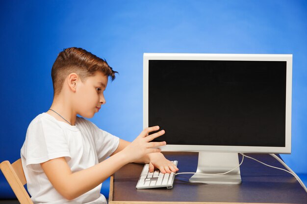 Niño en edad escolar sentado con el monitor portátil en el estudio