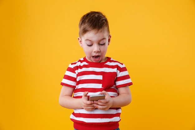 Foto gratuita niño emocionado inteligente leyendo el mensaje en el teléfono móvil