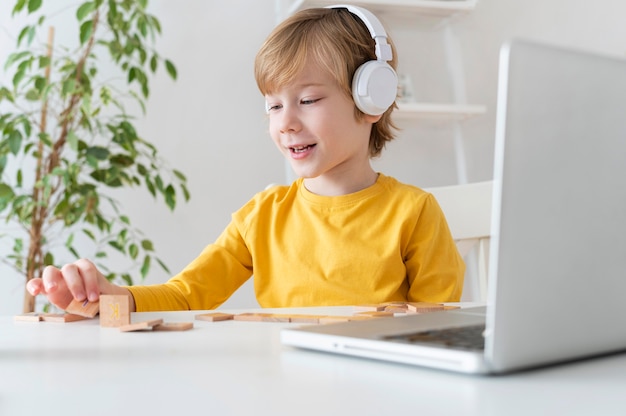 Niño emocionado con laptop y auriculares en casa