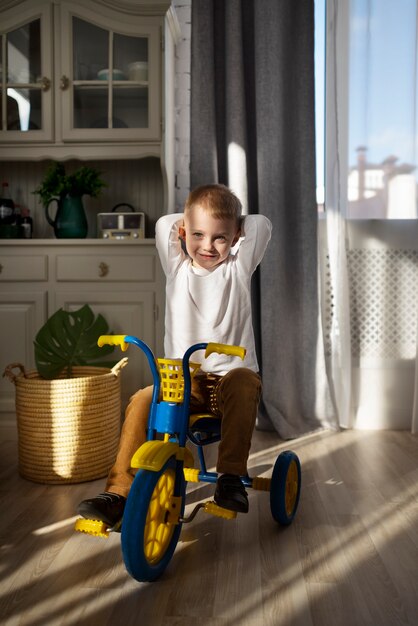 Niño emocionado de tiro completo en triciclo dentro