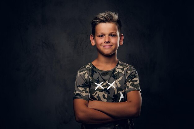 Un niño encantador con un bonito peinado posa sobre un fondo oscuro en el estudio fotográfico.