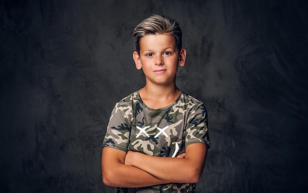 Un niño encantador con un bonito peinado posa sobre un fondo oscuro en el estudio fotográfico.