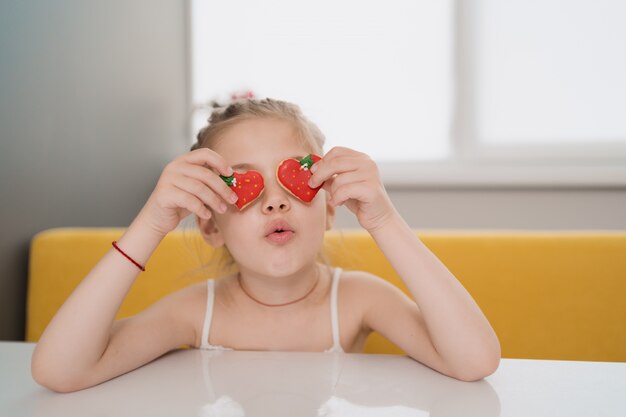 Niño encantador holdig galletas sobre los ojos