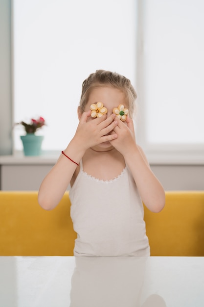 Niño encantador holdig galletas sobre los ojos