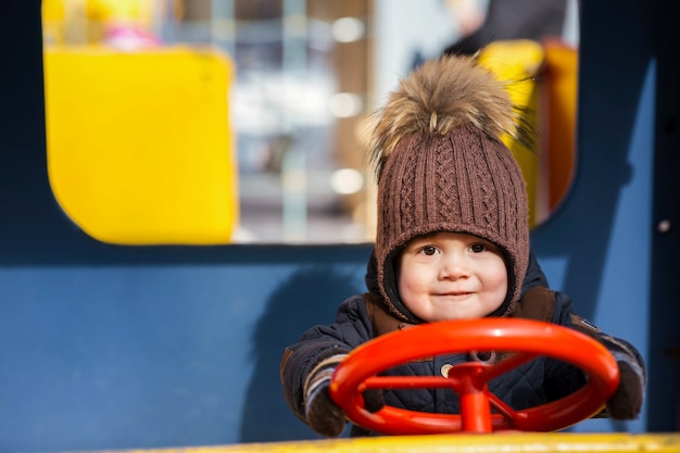 Niño encantador juega en el coche de juguete afuera