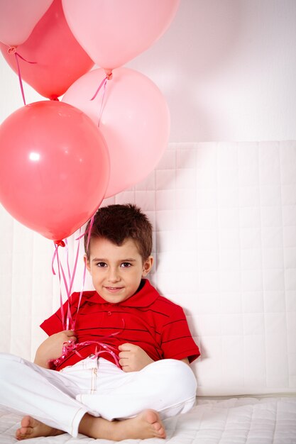 Niño encantador sujetando globos