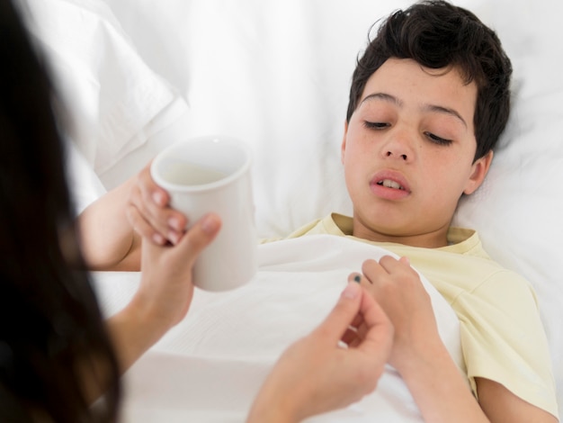 Foto gratuita niño enfermo de alto ángulo tomando píldora