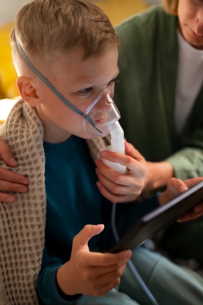 Foto gratuita niño enfermo de alto ángulo usando un nebulizador