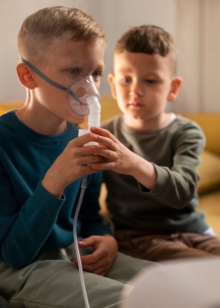 Niño enfermo de alto ángulo usando un nebulizador