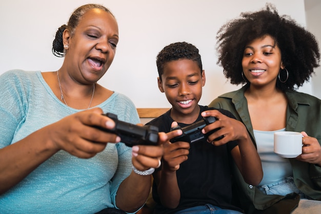Niño enseñando a la abuela y a la madre a jugar videojuegos.