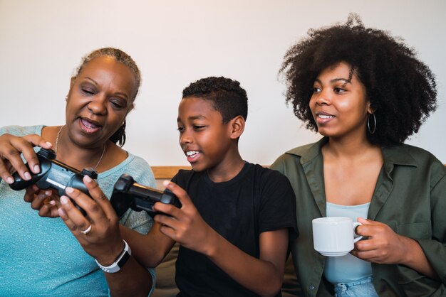 Niño enseñando a la abuela y a la madre a jugar videojuegos.