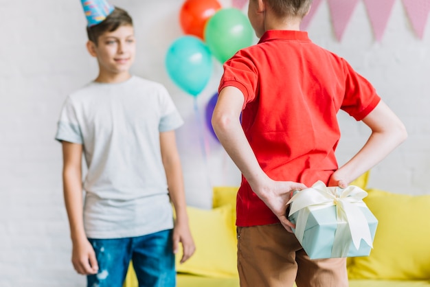 Foto gratuita niño escondido regalo de cumpleaños de su amigo