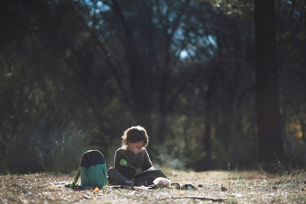 Niño escribiendo en el Bloc de notas en el bosque